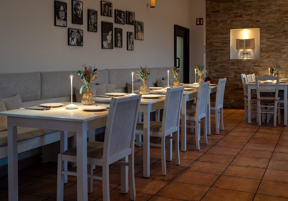 Gedeckter Gastraum des Restaurant Omega Moers mit Sitzbank und Bildern an der Wand