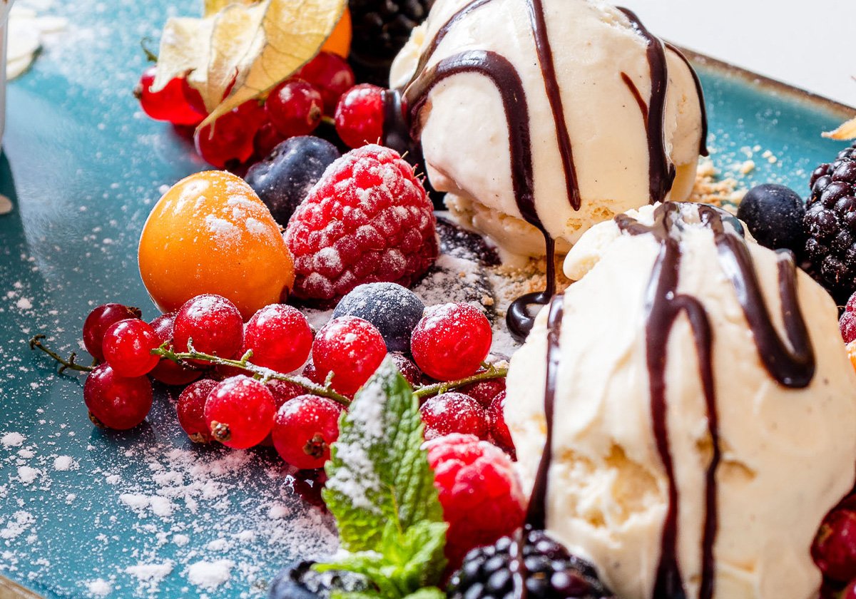 Vanilleeis mit Schokoladensauce und frischen Beeren als Dessert im Restaurant Omega Moers