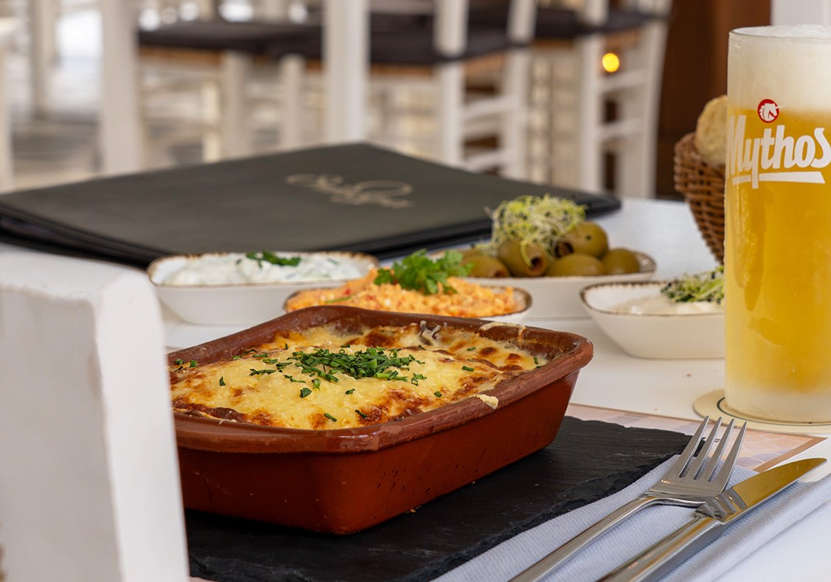 Überbackenes Moussaka in der Tonform mit Tzatziki, Oliven und Mythos-Bier im Restaurant Omega Moers